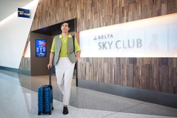 Man walking out of the Delta Sky Club with luggage